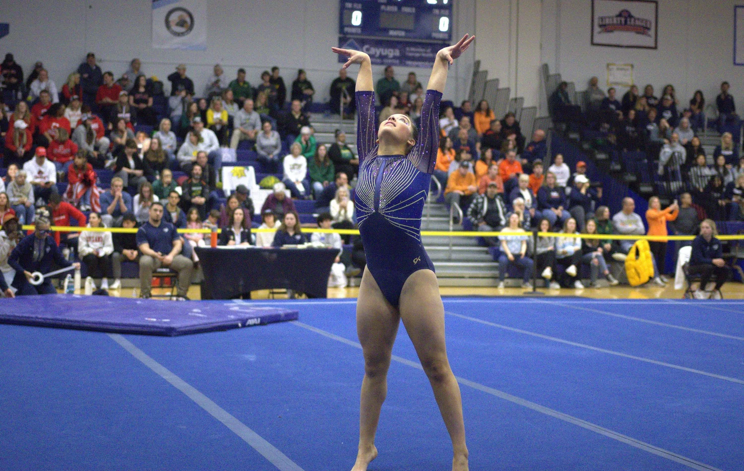 Photo of an Ithaca College gymnast performing on the floor in front of a crowd.